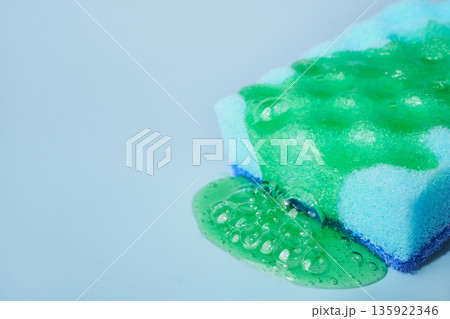 Colorful cleaning sponge with detergent foam on blue background Colorful cleaning sponge with detergent foam on blue background 135922346