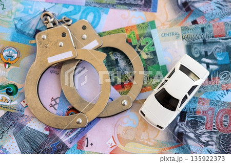 Kuwaiti dinar currency money bills and toy car with handcuffs close up. The concept of car accident Kuwaiti dinar currency money bills and toy car with handcuffs close up. The concept of car accident 135922373