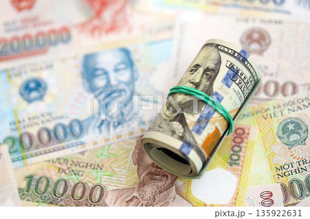 Vietnamese dong currency money bills and bunch of us dollar banknotes close up. The concept of economics and currency exchange Vietnamese dong currency money bills and bunch of us dollar banknotes close up. The concept of economics and currency exchange 135922631