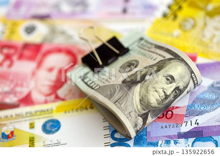 Philippines peso currency money bills and bunch of us dollar banknotes close up. The concept of economics and currency exchange Philippines peso currency money bills and bunch of us dollar banknotes close up. The concept of economics and currency exchange 135922656