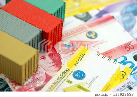 Philippines peso currency money bills and toy cargo containers close up. The concept of shipping and logistics 135922658