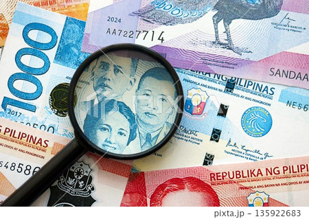Philippines peso currency money bills and magnifying glass close up. The concept of financial monitoring and taxation 135922683