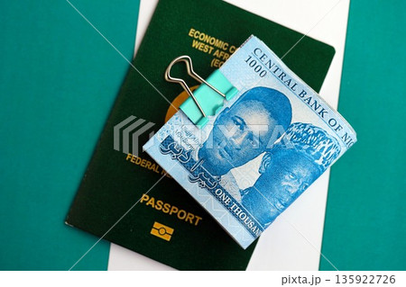 Nigerian naira currency money bills and passport lies on flag close up. The concept of travel and vacation Nigerian naira currency money bills and passport lies on flag close up. The concept of travel and vacation 135922726