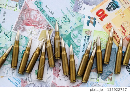Nigerian naira currency money bills and rifle bullets close up. The concept of warfare and gun selling Nigerian naira currency money bills and rifle bullets close up. The concept of warfare and gun selling 135922737
