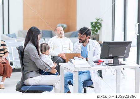 Pediatrician doctor consulting Asian mother about her little son health. Mother and son talking to therapist at consultation in hospital. Children healthcare concept. Pediatrician doctor consulting Asian mother about her little son health. Mother and son talking to therapist at consultation in hospital. Children healthcare concept. 135922866