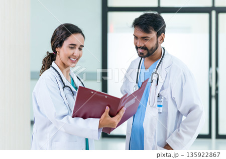 male and female doctors in white medical uniforms discuss patient anamnesis together. team brainstorming make decision concept. male and female doctors in white medical uniforms discuss patient anamnesis together. team brainstorming make decision concept. 135922867