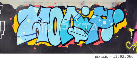 The old wall decorated with paint stains in the style of street art culture. Colorful background of full graffiti painting artwork with bright aerosol outlines on wall. Colored background texture The old wall decorated with paint stains in the style of street art culture. Colorful background of full graffiti painting artwork with bright aerosol outlines on wall. Colored background texture 135923060