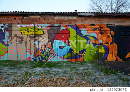The old wall decorated with paint stains in the style of street art culture. Colorful background of full graffiti painting artwork with bright aerosol outlines on wall. Colored background texture The old wall decorated with paint stains in the style of street art culture. Colorful background of full graffiti painting artwork with bright aerosol outlines on wall. Colored background texture 135923078