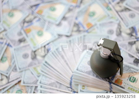 Grenade with a check against the background of huge amount of american dollar bills close up Grenade with a check against the background of huge amount of american dollar bills close up 135923258