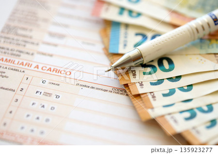 Filling italian tax form process with pen and euro money bills close up. Tax paying period and deadline Filling italian tax form process with pen and euro money bills close up. Tax paying period and deadline 135923277