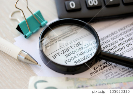 Information on revenue income derived by legal persons having no seats or place of management on territory of Poland IFT-2, IFT-2R form on accountant table with pen and polish zloty money bills 135923330