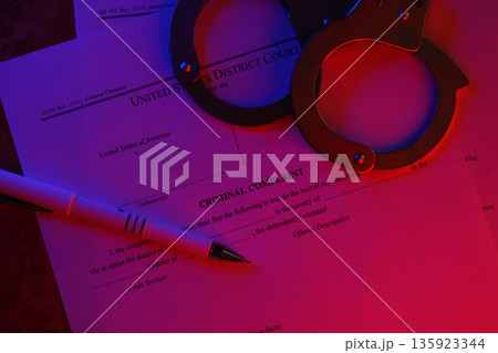 District Court Criminal complaint court papers with handcuffs and blue pen on table close up 135923344
