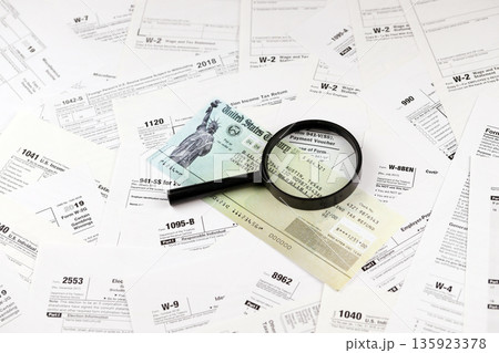Refund check on many tax form blanks lies on table close up. Tax payers paperwork routine and bureaucracy concept Refund check on many tax form blanks lies on table close up. Tax payers paperwork routine and bureaucracy concept 135923378