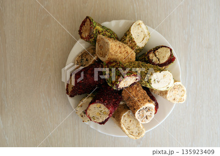 Many rolls of turkish delight with different flavors and fillings in white plate on table. Cuts of Turk Lokumu sweets 135923409