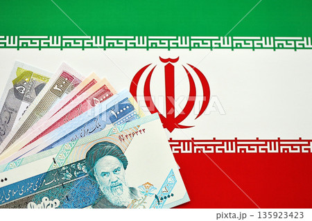 Iranian Rial IRR banknotes from Iran on flag of Islamic Republic of Iran close up Iranian Rial IRR banknotes from Iran on flag of Islamic Republic of Iran close up 135923423