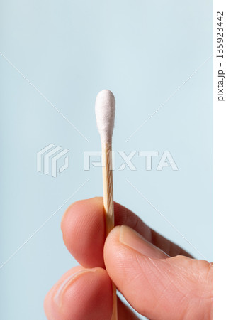Hand holding cotton swab for ear cleaning and hygiene Hand holding cotton swab for ear cleaning and hygiene 135923442