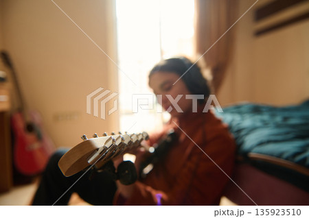 Teenage Musician in a Cozy Bedroom Playing Guitar, Quiet Focus and Passion Teenage Musician in a Cozy Bedroom Playing Guitar, Quiet Focus and Passion 135923510