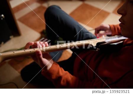Teenage Boy Playing Electric Guitar At Home, Focused On The Fretboard For A Hobby 135923521