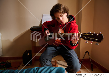 Teen Boy Plays Acoustic Guitar In Cozy Room, Hobby Music Session 135923538