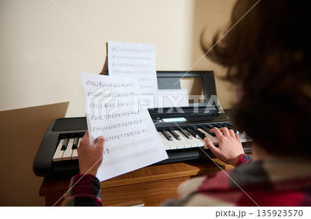 Teen Musician Playing Keyboard With Sheet Music At Home, Focused On Practice Teen Musician Playing Keyboard With Sheet Music At Home, Focused On Practice 135923570