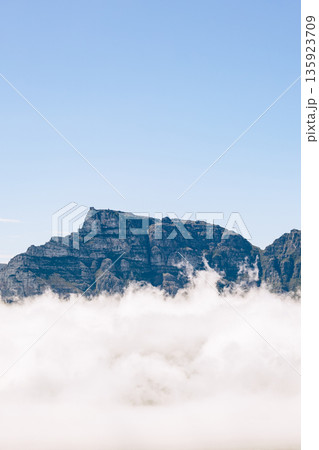 Panoramic view of Table Mountain above a thick blanket of clouds with clear blue sky. Helicopter tour over Cape Town, South Africa for a luxury vacation. 135923709