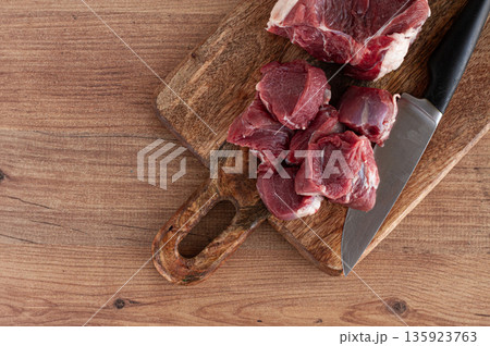 raw beef meat, sliced on a cutting board, with a knife, no spices, no herbs, top view, wooden table, homemade, no people, 135923763