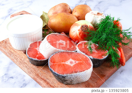 Fresh ingredients arranged on a wooden cutting board for cooking a meal in a bright kitchen setting Fresh ingredients arranged on a wooden cutting board for cooking a meal in a bright kitchen setting 135923805
