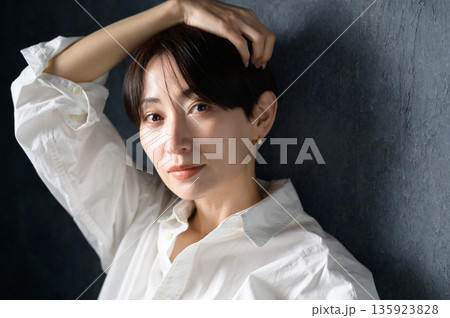 黒い背景でクールな表情の女性 135923828
