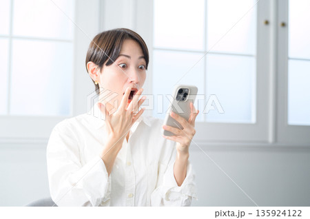 スマホを見てショックを受けるショートヘアの女性 135924122
