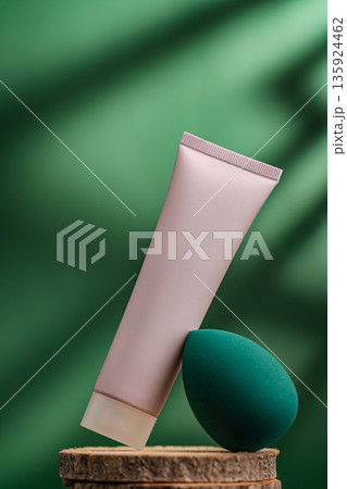Cosmetic tube and beauty sponge on natural wooden stand with green background Cosmetic tube and beauty sponge on natural wooden stand with green background 135924462