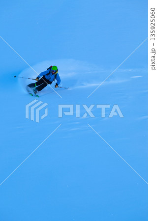 Skier carving fresh powder on a blue day, dynamic action in alpine terrain Skier carving fresh powder on a blue day, dynamic action in alpine terrain 135925060