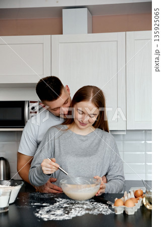 Couple enjoys cooking together in their kitchen while preparing a simple recipe during the afternoon Couple enjoys cooking together in their kitchen while preparing a simple recipe during the afternoon 135925065