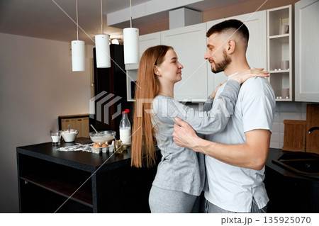 Couple sharing a moment in their kitchen while preparing breakfast on a weekend morning in a modern apartment setting Couple sharing a moment in their kitchen while preparing breakfast on a weekend morning in a modern apartment setting 135925070