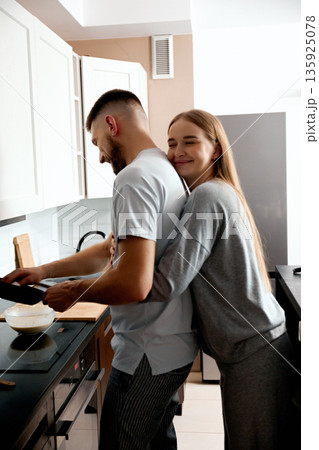 Couple cooking together in a home kitchen while enjoying each others company and sharing a moment of happiness in their daily routine Couple cooking together in a home kitchen while enjoying each others company and sharing a moment of happiness in their daily routine 135925078