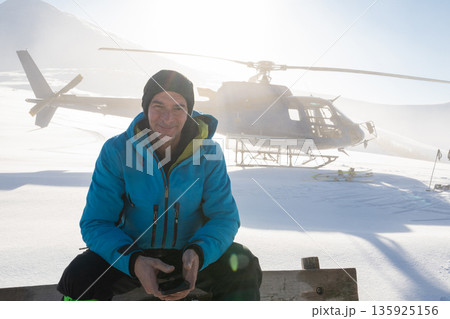 Offpiste heliskiing in fresh powder with a man and helicopter in the mountains Offpiste heliskiing in fresh powder with a man and helicopter in the mountains 135925156