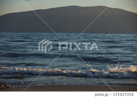 An evening view of the coastline of Vlora, Albania, taken in August 2025. Soft sunlight illuminates the rocky hills and seascape. 135925358
