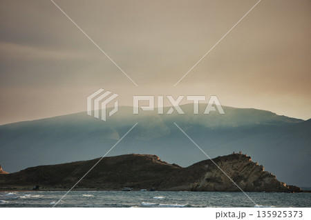 An evening view of the coastline of Vlora, Albania, taken in August 2025. Soft sunlight illuminates the rocky hills and seascape. An evening view of the coastline of Vlora, Albania, taken in August 2025. Soft sunlight illuminates the rocky hills and seascape. 135925373