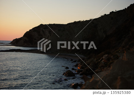 An evening view of the coastline of Vlora, Albania, taken in August 2025. Soft sunlight illuminates the rocky hills and seascape. An evening view of the coastline of Vlora, Albania, taken in August 2025. Soft sunlight illuminates the rocky hills and seascape. 135925380