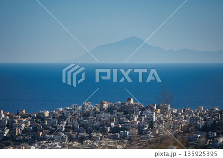 An evening view of the coastline of Vlora, Albania, taken in August 2025. Soft sunlight illuminates the rocky hills and seascape. 135925395