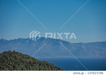 An evening view of the coastline of Vlora, Albania, taken in August 2025. Soft sunlight illuminates the rocky hills and seascape. 135925396
