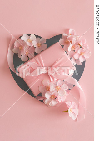 Blue Heart Cutout. Romantic Valentines Day Flatlay with Gift Box and Cherry Blossom on Pink Background Blue Heart Cutout. Romantic Valentines Day Flatlay with Gift Box and Cherry Blossom on Pink Background 135925620