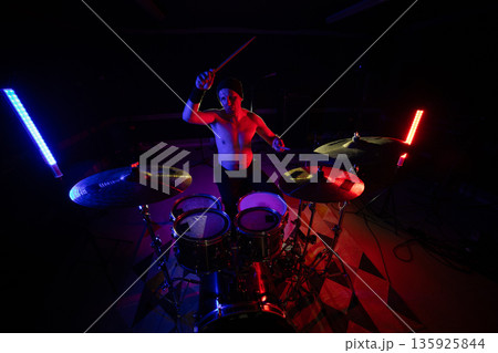 Drummer playing live music with colorful stage lighting Drummer playing live music with colorful stage lighting 135925844