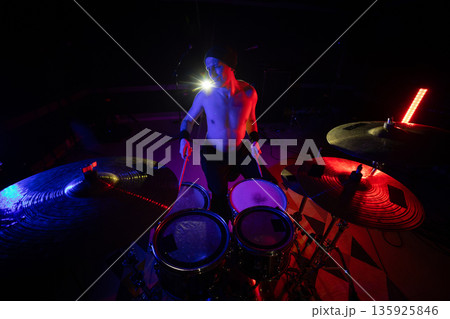 Drummer performing live on stage with vibrant lights 135925846