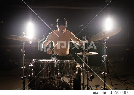 Drummer playing a drum set with backlights 135925872