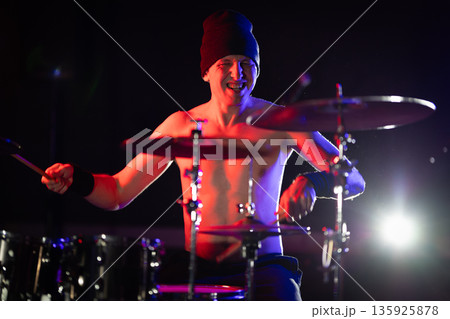 Enthusiastic drummer playing live music on stage smiling 135925878