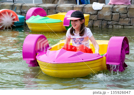 Kid playing rowing water paddle boat. Soft focus. A little girl rides a colorful boat on a pool in a resort. High quality photo Kid playing rowing water paddle boat. Soft focus. A little girl rides a colorful boat on a pool in a resort. High quality photo 135926047