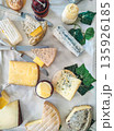 Assorted cheese platter with various French cheese types, knives, and jars of jam arranged on a white tablecloth 135926185