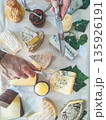 Assorted French cheese platter with various types of cheese, knife, and jam, hands preparing to serve 135926191