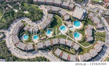 Aerial view of a residential area in Albufeira, Portugal, featuring multiple buildings and circular swimming pools surrounded by trees Aerial view of a residential area in Albufeira, Portugal, featuring multiple buildings and circular swimming pools surrounded by trees 135926304