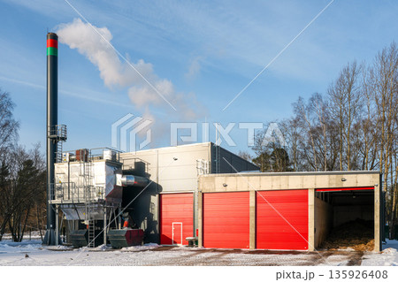 Modern wood chip boiler house with biomass heating system and red storage doors in winter Modern wood chip boiler house with biomass heating system and red storage doors in winter 135926408
